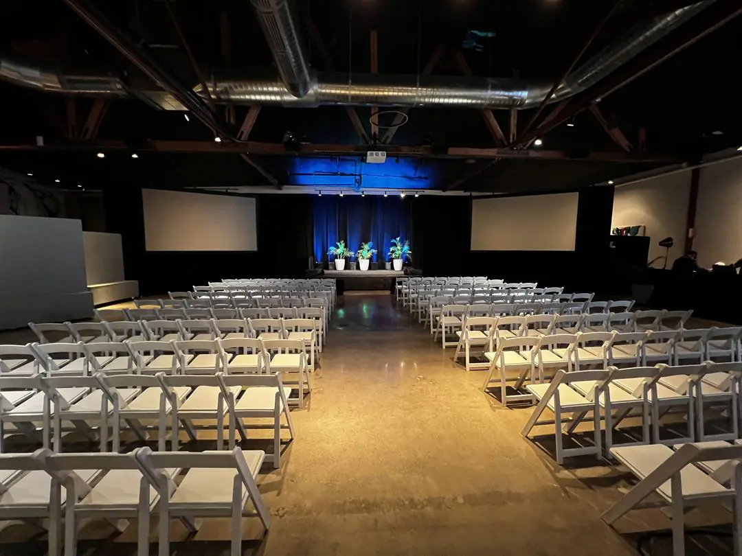 An Empty Room With a Line of White Chairs
